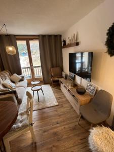 a living room with a couch and a tv at Studio Auron 4 couchages in Saint-Étienne-de-Tinée