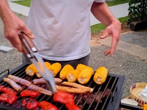 a man cooking sausages and hot dogs on a grill at Badulla Bliss in Badulla