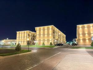 two tall buildings are lit up at night at Туркестан VIP КАРАВАН in Türkistan