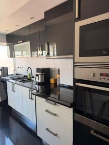 a kitchen with white cabinets and a microwave at Cozy Apartment Almada in Almada