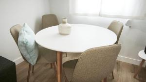 a white table with chairs and a bottle on it at La Ilusión in Sanxenxo