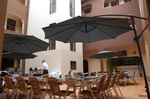 a man standing in front of tables and chairs with umbrellas at Sky Hotels Emali in Mwanda