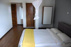 a bedroom with a bed with a yellow blanket and a mirror at Sky Hotels Emali in Mwanda