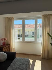 a living room with a large window and a couch at Cozy Apartment Almada in Almada
