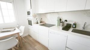 a white kitchen with white cabinets and a sink at La Ilusión in Sanxenxo +19 photos