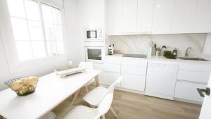 a white kitchen with white cabinets and a table and chairs at La Ilusión in Sanxenxo