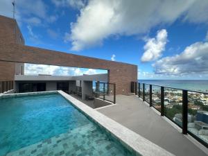 a swimming pool on top of a building with the ocean at View Soft House - Quarto e Sala 213 in Lauro de Freitas