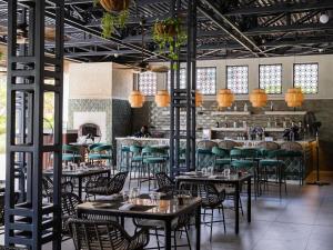 a dining room with tables and green chairs at Mövenpick Ambassador Hotel Accra in Accra