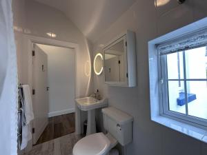 a bathroom with a toilet and a sink and a window at Guinness House in Ballyconneely +57 photos