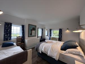 a bedroom with two beds and two windows at Guinness House in Ballyconneely