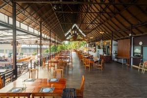 a restaurant with wooden tables and chairs and a long room at Champasak Grand Hotel in Pakse