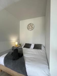 a bedroom with a white bed and a clock on the wall at Le Cocon Cornouaillais, hyper centre, parking pv in Quimper