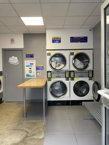 a laundry room with three washing machines and a table at Le Cocon Cornouaillais, hyper centre, parking pv in Quimper