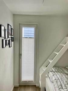 a white bedroom with a bed and a window at AURORA in Lübeck