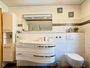a bathroom with a sink and a toilet and a mirror at Ferienwohnung Wohlfühloase - gemütliche Familienunterkunft in ruhiger Lage in Achberg +15 photos