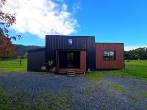 a black and red house on a field at Luxe Tiny Home in Whangarei