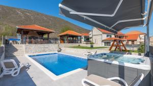 a swimming pool with chairs and an umbrella at Villa Ivandvor in Split by Villas Guide in Radošić