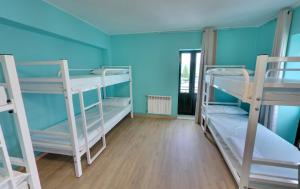 a room with three bunk beds and a blue wall at ALBERGUE Pasiño A Pasiño in Portomarin +15 photos