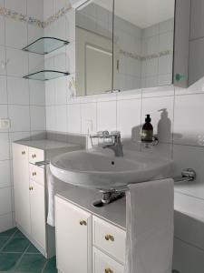 a white bathroom with a sink and a mirror at Residenza delle Fonti by HolAp SA in Minusio +21 photos