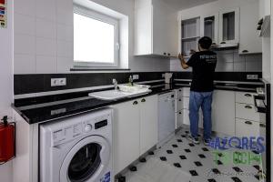 a man standing in a kitchen looking into a window at Casa da Misericordia in Praia da Vitória
