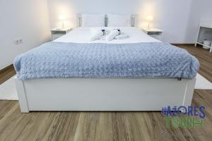 a large white bed with a blue blanket on it at Casa da Misericordia in Praia da Vitória