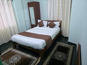 a bedroom with a large bed with brown and white sheets at Tree Top Residency in Mysore