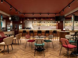 a restaurant with tables and chairs and a bar at Mövenpick Hotel Budapest Centre in Budapest