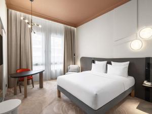 a hotel room with a white bed and a table at Mövenpick Hotel Budapest Centre in Budapest