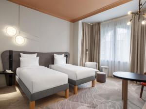 a hotel room with two beds and a table at Mövenpick Hotel Budapest Centre in Budapest +87 photos