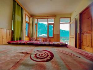 a large bedroom with a large bed in a room with windows at Negi Wooden House in Manāli