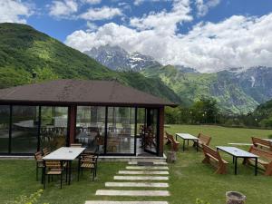 a gazebo with tables and chairs and mountains at Shpija Ujevara e Vogel 2 in Theth