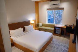 a bedroom with a bed and a couch and a window at Central Residence by Paramount Hospitality in Karachi