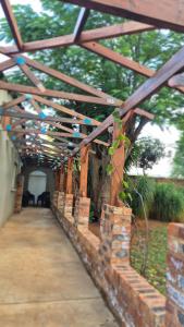 a brick walkway with a wooden roof and trees at Herberg 1 in De Wildt