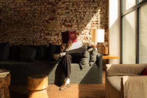 a person laying on a couch reading a book at 9Hotel Central in Brussels