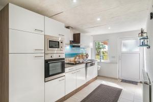 a white kitchen with white appliances and a window at Ferienwohnung Koje 1 in Wangerland