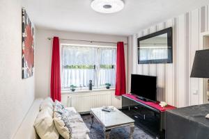 a living room with red curtains and a television at Ferienwohnung Koje 1 in Wangerland