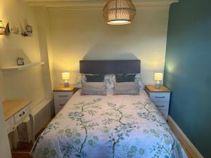 a bedroom with a bed with two lamps on it at Boatman's Cottage in Rhoscolyn