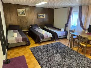 a room with two beds and a table and a desk at Sandby in Karlholmsbruk