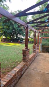 a wooden pergola in a park with a grass field at Herberg 1 in De Wildt