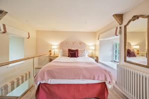 a bedroom with a large bed and a mirror at Piddle Cottage in Dorchester