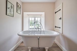 a white bath tub in a bathroom with a window at Piddle Cottage in Dorchester +33 photos