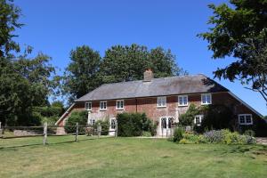 an old red brick house with a green yard at Piddle Cottage in Dorchester
