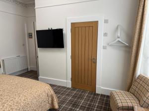 a bedroom with a bed and a television on a wall at Sandvilla Guesthouse in Oban