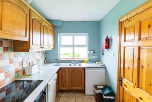 a kitchen with blue walls and a sink and a window at Blasket Cottage - Portmagee in Lateeve +26 photos
