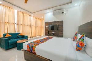 a bedroom with a large bed and a blue chair at Hotel Vihara Inn in Bangalore +4 photos
