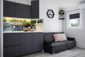 a kitchen with black cabinets and a couch and a sink at Aura Luxury Suites Bled in Bled