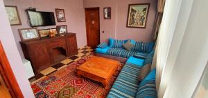 a living room with a blue couch and a tv at Domaine Couleurs Berbères, Piscine, Vue Atlas, Bivouac & Expériences à Lalla Takerkoust in Lalla Takerkoust