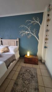 a bedroom with a bed with a tree mural on the wall at Herberg 5 in Vosburg