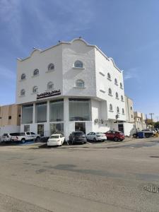 a large white building with cars parked in a parking lot at أصالة الشروق حائل in Hail