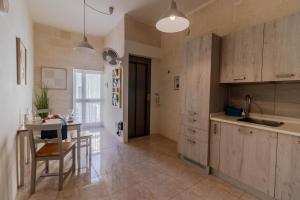 a kitchen with wooden cabinets and a table with chairs at Sea Steps Marsalforn in Marsalforn